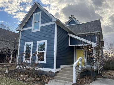 Charming two-story home with blue siding, white trim, a bright yellow door, and manicured landscaping at 1424 S New Jersey St, Indianapolis, IN 46225