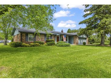 Charming single-story brick home featuring a well-manicured lawn, mature trees, and an attached two-car garage at 2818 S Irwin St, Indianapolis, IN 46203