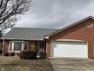 Charming brick home featuring an attached two-car garage, a well-maintained lawn, and a cozy bay window at 320 Lakewood Ct, Avon, IN 46123