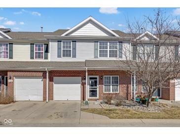 Charming two-story townhouse features a brick facade and a one-car garage, nestled under a partly cloudy sky at 9730 Prairie Smoke Dr, Noblesville, IN 46060