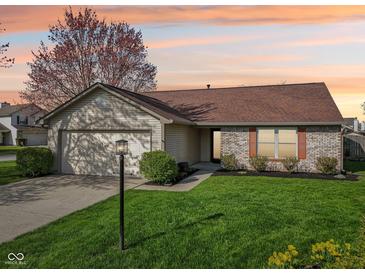 Charming single-Gathering home featuring a manicured lawn, attached garage, and brick accents under a colorful sunset at 2020 Cross Willow Ln, Indianapolis, IN 46239