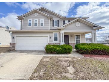 Charming two-story home featuring a covered entryway, attached garage, and well-maintained landscaping at 3941 Planewood Dr, Indianapolis, IN 46235