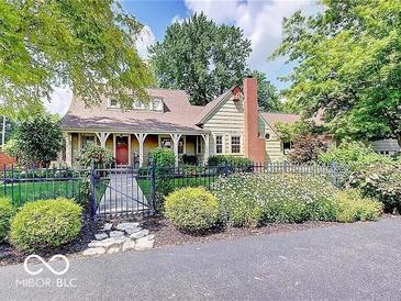Charming home featuring a red brick chimney, inviting front porch, and lush landscaped yard at 5055 Willow Rd, Zionsville, IN 46077