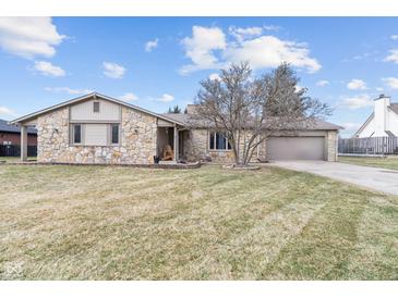 Charming stone home with an attached garage, mature landscaping and a cozy front porch seating area at 6412 Lava Ct, Indianapolis, IN 46237