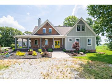 Charming home featuring a mix of brick and siding, a cozy front porch and a bright, yellow front door at 695 N 650 W, Lebanon, IN 46052