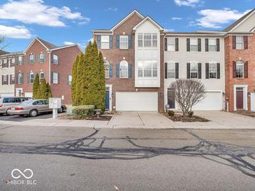 Charming townhome featuring brick facade, attached garage, and well-maintained landscaping at 11936 Esty Way, Carmel, IN 46033