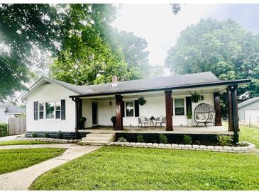 Charming home featuring a covered front porch with stylish seating and beautifully landscaped front yard at 504 S Main St, Waldron, IN 46182