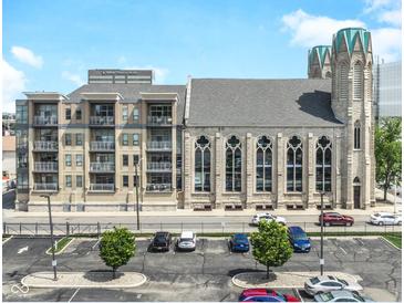 An exterior view of a modern apartment building attached to a historic church with ample parking at 802 N Meridian St # 205, Indianapolis, IN 46204