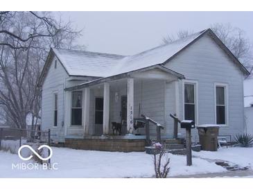 Quaint two-story home featuring a porch and classic architecture, covered in snow at 1516 Sycamore St, Columbus, IN 47201