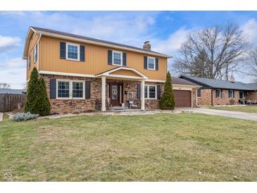 Charming two-story home featuring a brick and siding exterior, complemented by a well-manicured lawn and mature landscaping at 5529 W 29Th Pl, Indianapolis, IN 46224