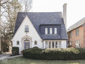 Charming home with a beautiful slate roof, arched doorway, and manicured landscaping creating curb appeal at 6009 N Washington Blvd, Indianapolis, IN 46220