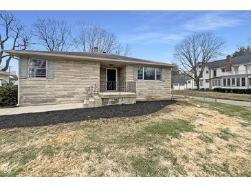 Charming single-story home with stone facade, well-manicured front yard and minimalist landscaping at 1221 Kessler Blvd E Dr, Indianapolis, IN 46220