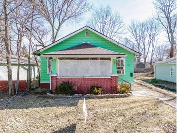 Charming home features a cozy covered porch with brick accents and a well-maintained front yard, ready for personalization at 3455 Hillside Ave, Indianapolis, IN 46218