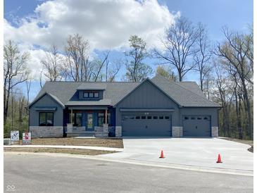 New construction home boasts a three-car garage, stone accents, and a welcoming front porch at 3604 Maple Ridge Dr, Columbus, IN 47201