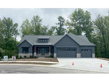 Charming one-story home boasts a gray exterior, three-car garage, and stone accents at 3604 Maple Ridge Dr, Columbus, IN 47201