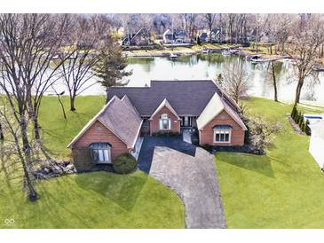 Aerial view of a waterfront home with a red brick exterior, well-manicured lawn, and a long driveway leading to the house at 5519 Fall Creek Rd, Indianapolis, IN 46220