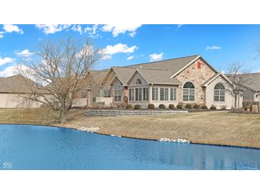 Charming exterior view of a stone and siding home with a beautiful pond in the front yard at 7914 King Post Dr, Indianapolis, IN 46237