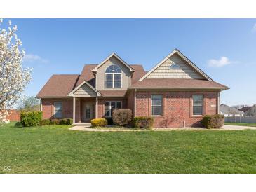 Charming brick two-story home with manicured lawn and mature tree against a clear blue sky at 2838 Violet W Ct, Columbus, IN 47201