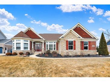 Charming single-story home with stone and red siding, complemented by a well-manicured lawn and blue sky at 3924 Bear Creek Way, Carmel, IN 46074