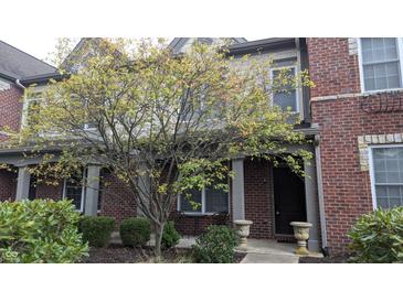Brick townhome exterior featuring a covered entryway and well-maintained landscaping in a residential community at 6691 Beekman Pl, Zionsville, IN 46077