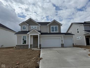 Charming two-story home featuring a three car garage and stylish stone accents, complemented by a cozy front porch at 7156 Firestone Rd, Whitestown, IN 46052