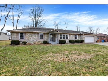 Charming single-story stone house with well-maintained front yard and attached two-car garage at 725 Queenswood Dr, Indianapolis, IN 46217
