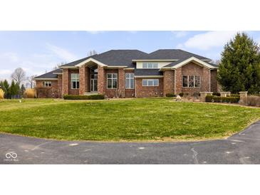 Stunning brick home features a lush lawn, mature trees, and an inviting circular driveway at 8810 E 200 S, Zionsville, IN 46077