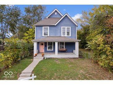 Charming blue two-story home featuring a cozy front porch with swing and manicured lawn at 2528 Guilford Ave, Indianapolis, IN 46205