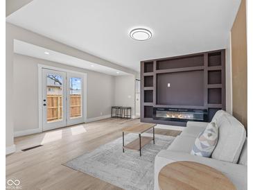 Bright living room featuring a decorative fireplace wall and wood-look flooring at 714 S Keystone Ave, Indianapolis, IN 46203