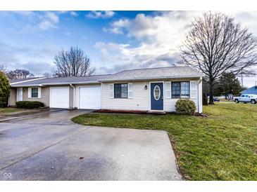 Charming one-story home features a front lawn, driveway, garage, and classic architecture under a cloudy sky at 8004 Minlo Dr, Indianapolis, IN 46227