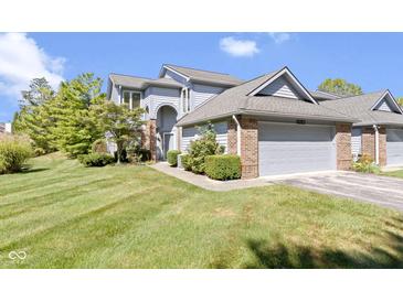 Inviting two-story townhome boasts a brick-accented garage, manicured lawn, and blue siding at 8212 Nekton Ln, Indianapolis, IN 46236