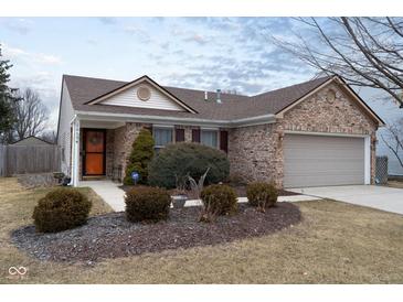 Charming single-story brick home featuring a well-manicured lawn and attached two-car garage at 10154 Holly Berry Cir, Fishers, IN 46038