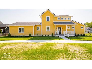 Inviting yellow two-story home with a charming front porch and well-manicured lawn at 10483 St Anne Dr, Zionsville, IN 46077