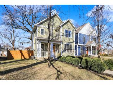 Charming two-story home boasts a manicured lawn, complemented by lush green bushes and an inviting front porch at 1422 Carrollton Ave, Indianapolis, IN 46202