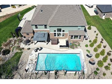 Stunning aerial view of backyard featuring a large swimming pool, patio with outdoor kitchen, and well-manicured lawn at 5683 Oakmont Blvd, Bargersville, IN 46106