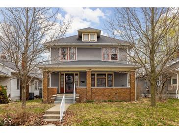 Charming two-story home featuring a covered porch and mature trees in a well-maintained front yard at 825 N Bancroft St, Indianapolis, IN 46201