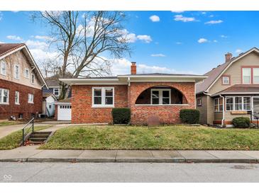 Charming brick home featuring a cozy front porch, complemented by manicured landscaping and a well-maintained lawn at 959 E Bradbury Ave, Indianapolis, IN 46203