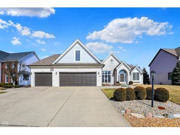 Charming brick home with a well-manicured lawn and a three-car garage, enhanced by a blue sky filled with fluffy clouds at 10896 Fairwoods Dr, Fishers, IN 46037