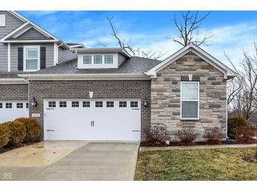 Charming townhome showcasing a two-car garage, stone facade, and well-maintained landscaping at 14474 Treasure Creek Ln, Fishers, IN 46038