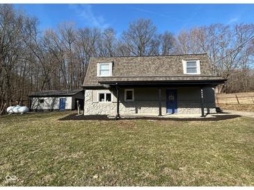 Charming home featuring stone accents, a covered porch, and a detached garage, nestled among mature trees at 8468 N Baltimore Rd, Monrovia, IN 46157