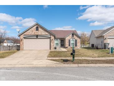 Charming brick home featuring an attached two car garage and well-maintained lawn at 4313 Strawflower Dr, Indianapolis, IN 46203