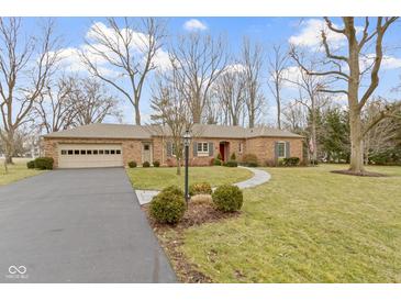 Charming brick home with attached garage, manicured lawn, and inviting walkway at 7481 Holliday E Dr, Indianapolis, IN 46260