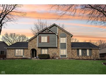 Charming two-story stone and wood home with a well-maintained lawn and colorful sunset sky at 9132 Log Run N Dr, Indianapolis, IN 46234