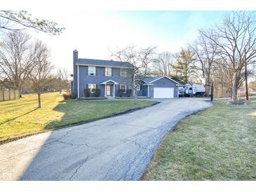 Charming blue home featuring an attached garage, long driveway, and ample yard space at 8513 Shelbyville Rd, Indianapolis, IN 46259
