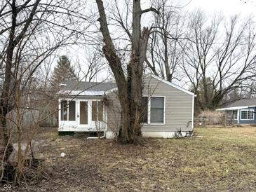 A modest home with light siding and a cozy sunroom, surrounded by mature trees in a quiet setting at 1126 N Mitthoeffer Rd, Indianapolis, IN 46229