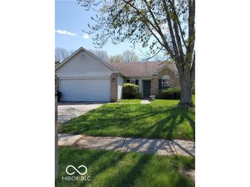 Charming single-story home with a well-maintained lawn, attached garage, and inviting entryway at 5851 Brobeck Ln, Indianapolis, IN 46254