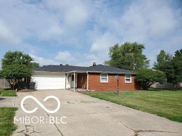 Charming single-story home featuring a red brick facade, attached garage, and well-manicured front lawn at 6721 Jackson St, Anderson, IN 46013