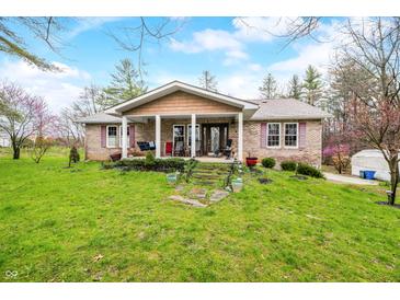Charming brick home featuring a covered porch and a well-maintained front yard with mature trees and landscaping at 1794 Bell Rd, Morgantown, IN 46160