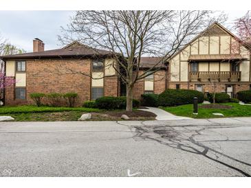 Brick townhouse features a walkway and a neatly landscaped front yard with mature trees and flowering shrubs at 3840 Knollton Rd # A, Indianapolis, IN 46228