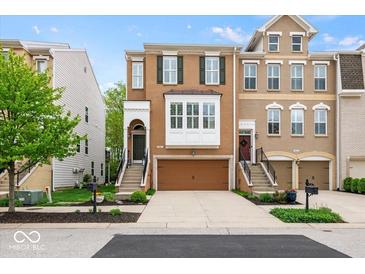 Charming brick townhome featuring a two-car garage, covered entrance, and well-manicured landscaping at 681 Greenford N Trl, Carmel, IN 46032